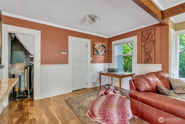 living area featuring wainscoting, wood finished floors, ornamental molding, and a ceiling fan