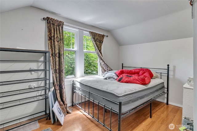 bedroom with vaulted ceiling and light wood-style flooring