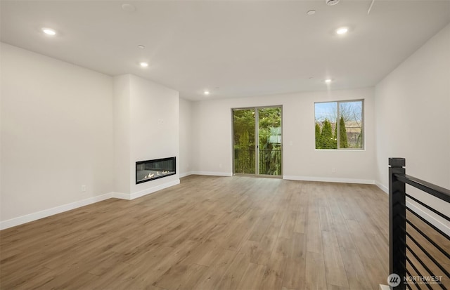 26539 NE 143rd Cir Unit E, Duvall, WA 98019 - unfurnished living room with a glass covered fireplace, recessed lighting, light wood-style flooring, and baseboards