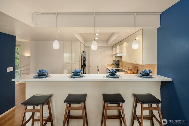 2400 Aurora Ave N Unit 202, Seattle, WA 98109 - kitchen with a peninsula, white cabinets, light countertops, and a breakfast bar area