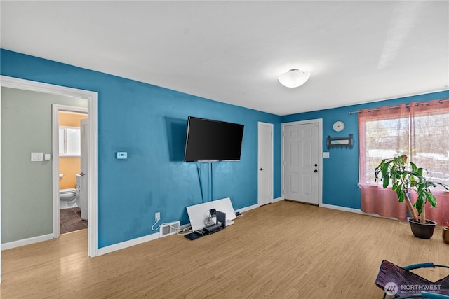 unfurnished living room with wood finished floors and baseboards