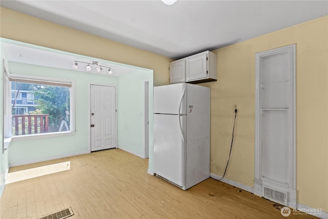 kitchen featuring freestanding refrigerator, light wood-style floors, baseboards, and white cabinetry