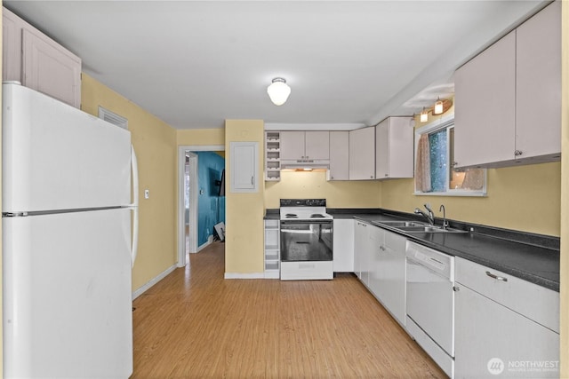 kitchen with white appliances, under cabinet range hood, dark countertops, a sink, and light wood-style flooring
