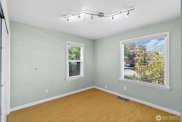 unfurnished room with light wood-style floors, baseboards, and rail lighting