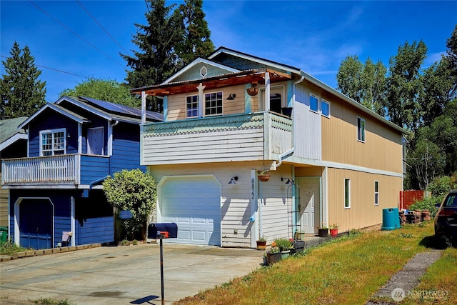 view of front of property featuring a balcony, an attached garage, and concrete driveway