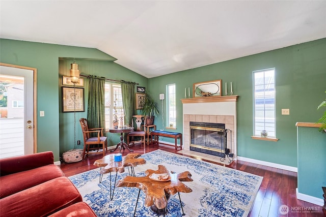 living area featuring a fireplace, wood finished floors, vaulted ceiling, and baseboards