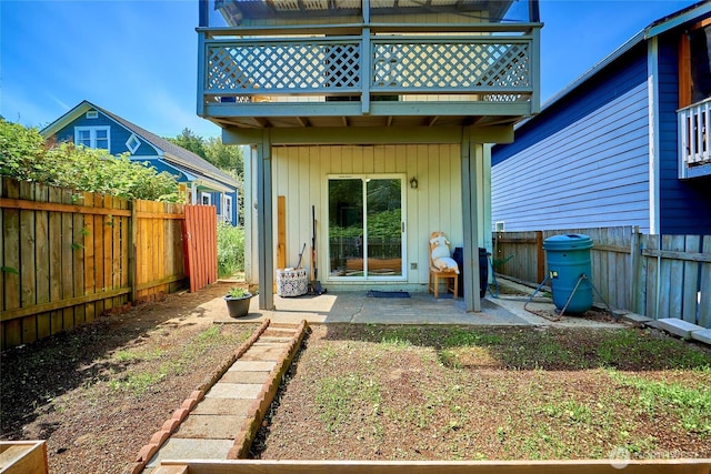 rear view of house with a balcony, a patio area, and a fenced backyard