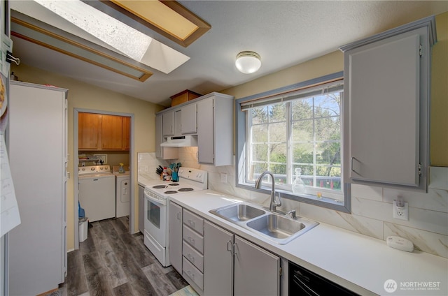 1510 144th Ln, Long Beach, WA 98631 - kitchen featuring white range with electric stovetop, washing machine and clothes dryer, a sink, under cabinet range hood, and tasteful backsplash