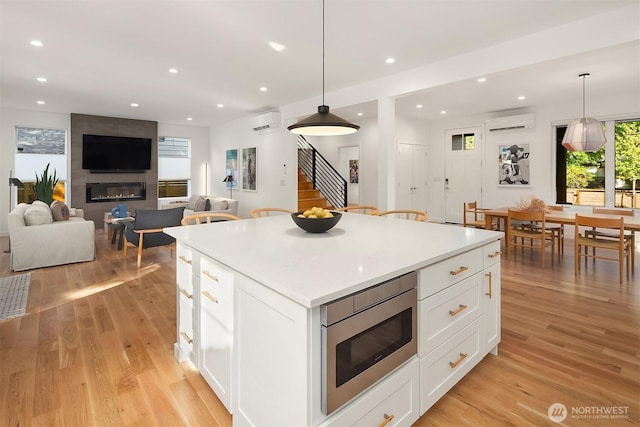 10419 41st Ave SW Unit A, Seattle, WA 98146 - kitchen with stainless steel microwave, an AC wall unit, recessed lighting, and light wood-type flooring