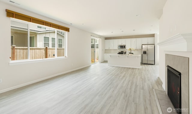 6146 Windlass Ave SE, Port Orchard, WA 98367 - unfurnished living room with light wood-type flooring, a fireplace, baseboards, and a sink