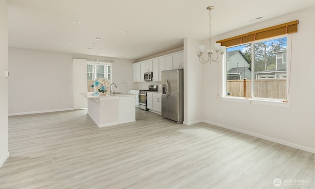 6146 Windlass Ave SE, Port Orchard, WA 98367 - kitchen with appliances with stainless steel finishes, a chandelier, baseboards, white cabinetry, and light wood-type flooring