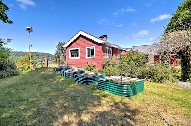 8820 E State Route 106, Union, WA 98592 - rear view of house with a garden, a lawn, and a chimney