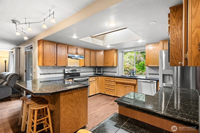5102 23rd Ave SE, Lacey, WA 98503 - kitchen featuring appliances with stainless steel finishes, under cabinet range hood, tile countertops, a peninsula, and a sink