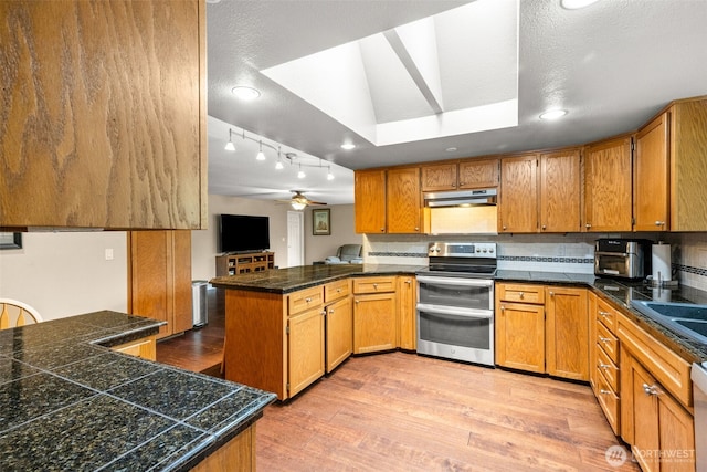 5102 23rd Ave SE, Lacey, WA 98503 - kitchen with appliances with stainless steel finishes, a peninsula, under cabinet range hood, light wood-style floors, and brown cabinets