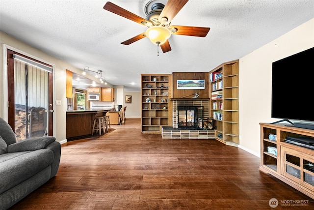 5102 23rd Ave SE, Lacey, WA 98503 - living room featuring a fireplace, a textured ceiling, ceiling fan, wood finished floors, and baseboards