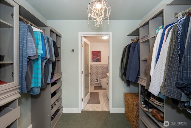 walk in closet featuring a chandelier and dark colored carpet