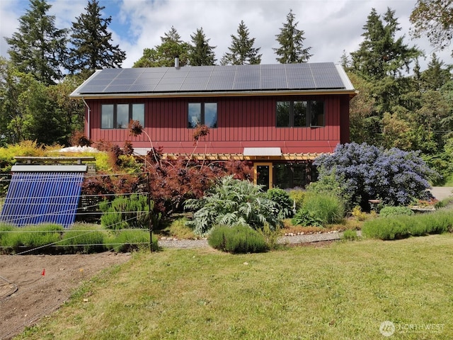 11191 Valley Heights Cir NE, Bainbridge Island, WA 98110 - view of front facade featuring roof mounted solar panels, a front lawn, board and batten siding, and central AC