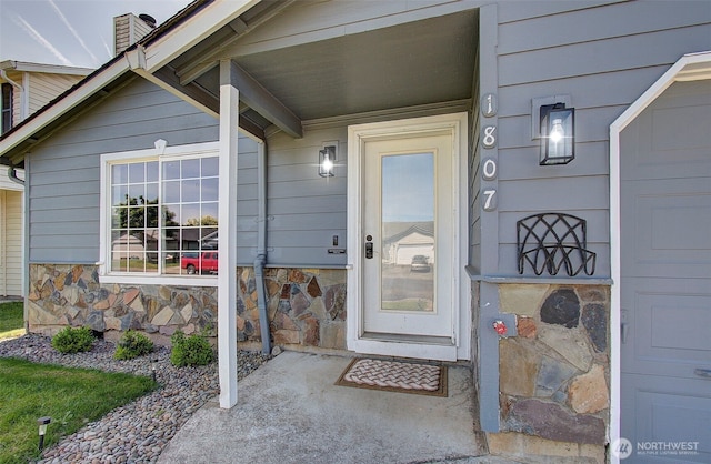 property entrance featuring a chimney and stone siding