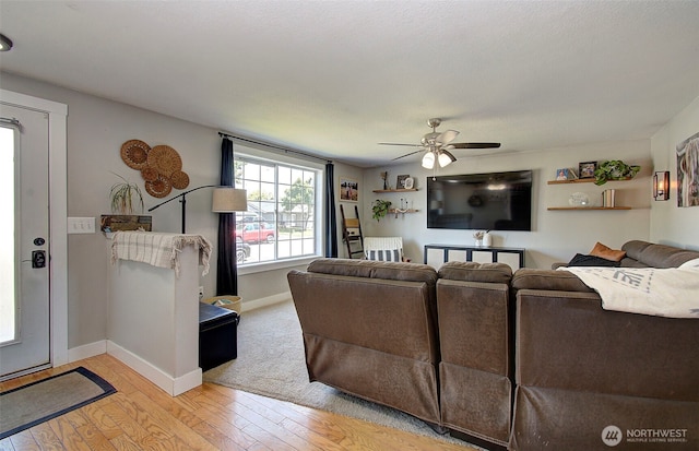 living room featuring a ceiling fan, light wood-type flooring, and baseboards