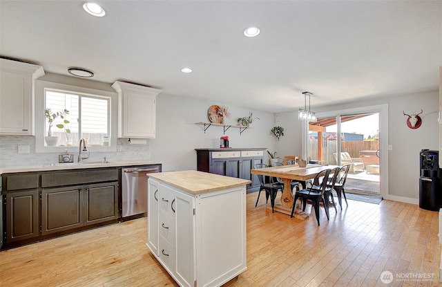 kitchen with a sink, stainless steel dishwasher, white cabinetry, light wood-style flooring, and recessed lighting