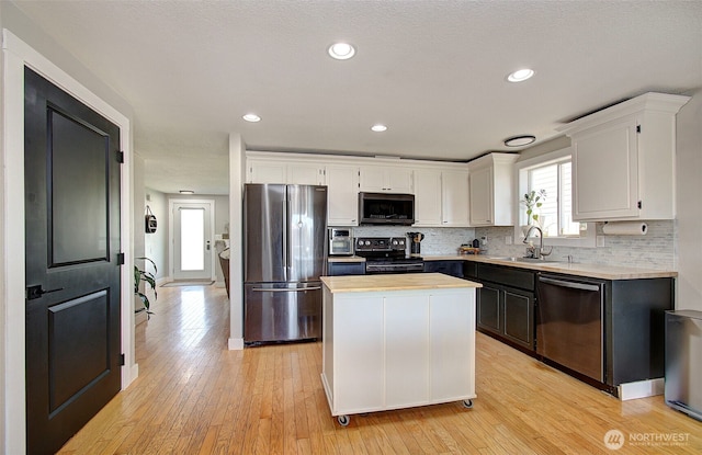 kitchen with appliances with stainless steel finishes, a sink, white cabinetry, decorative backsplash, and recessed lighting