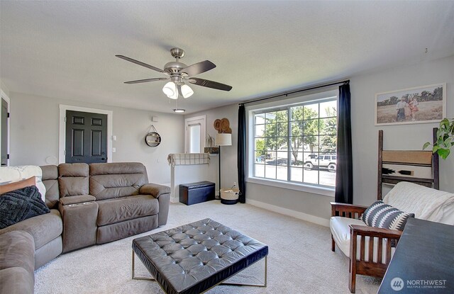 living area with light colored carpet, a ceiling fan, and baseboards