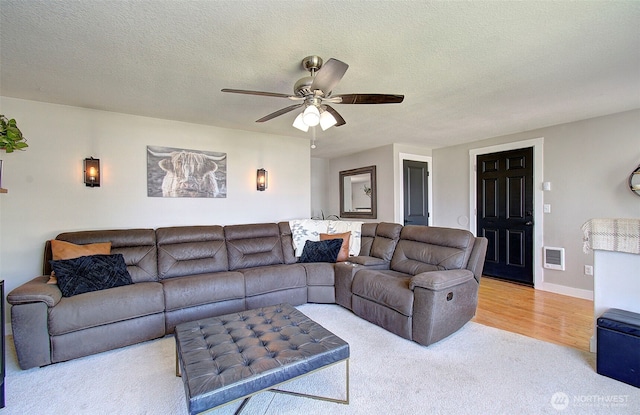 living area featuring carpet, ceiling fan, a textured ceiling, and baseboards