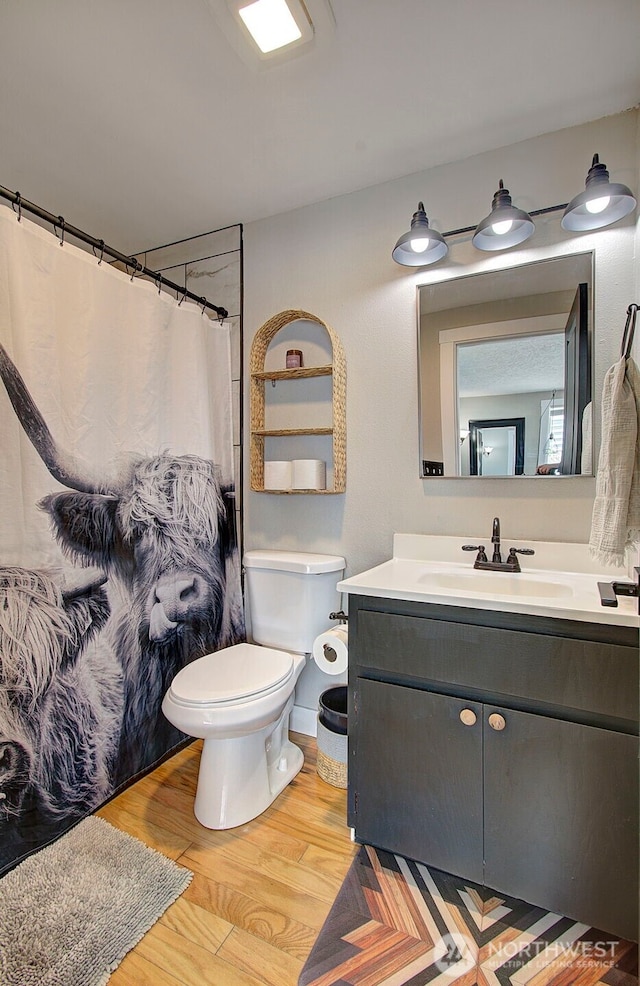 full bathroom featuring wood finished floors, toilet, vanity, and a shower with shower curtain