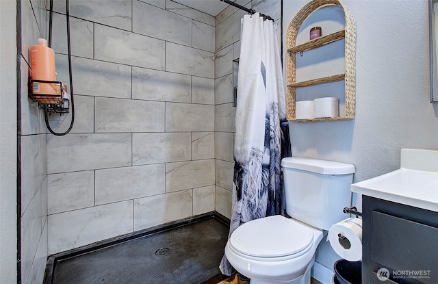 full bath featuring a tile shower, toilet, and vanity