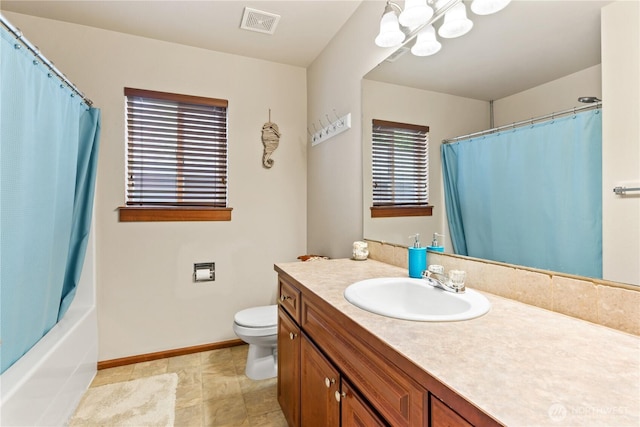 bathroom with toilet, a chandelier, vanity, baseboards, and shower / tub combo