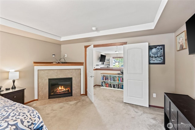 bedroom featuring light carpet, baseboards, and a tile fireplace