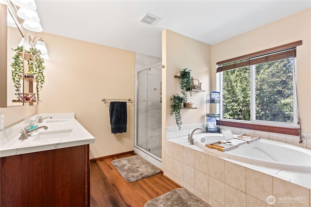 full bath with wood finished floors, a stall shower, a garden tub, and double vanity