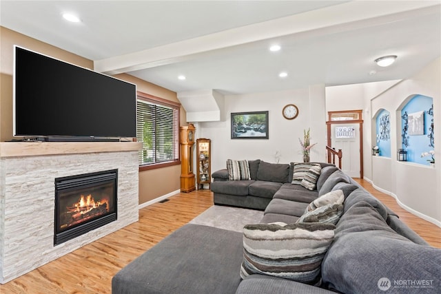 living room featuring light wood-style floors, a stone fireplace, recessed lighting, and baseboards