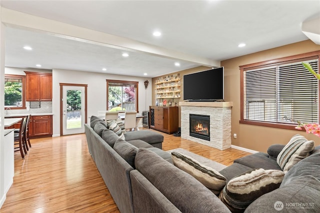 living room featuring recessed lighting, light wood finished floors, beam ceiling, baseboards, and a fireplace