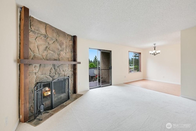 12525 NE 145th Pl Unit F105, Kirkland, WA 98034 - unfurnished living room featuring a chandelier, carpet flooring, a stone fireplace, and a textured ceiling