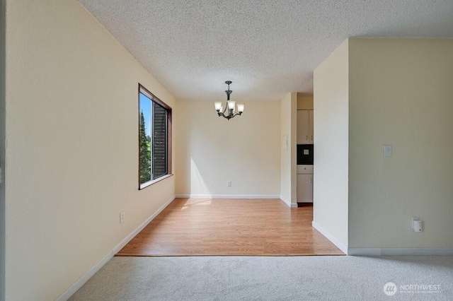 12525 NE 145th Pl Unit F105, Kirkland, WA 98034 - spare room featuring a chandelier, a textured ceiling, light colored carpet, and baseboards