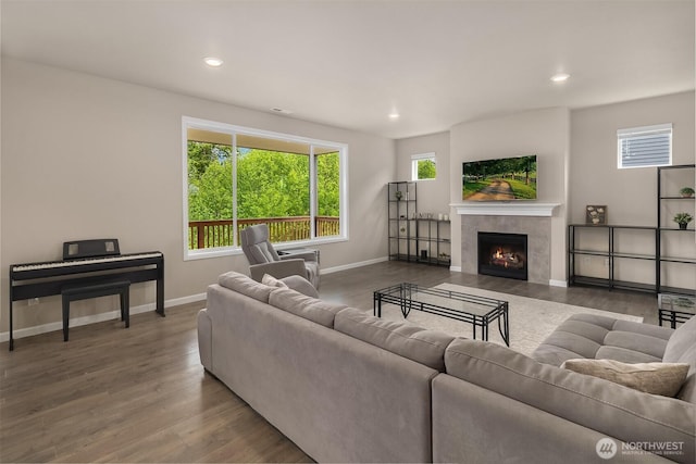 living area featuring baseboards, recessed lighting, wood finished floors, and a tile fireplace