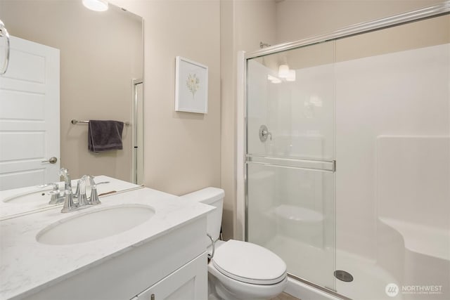 bathroom with a shower stall, toilet, and vanity