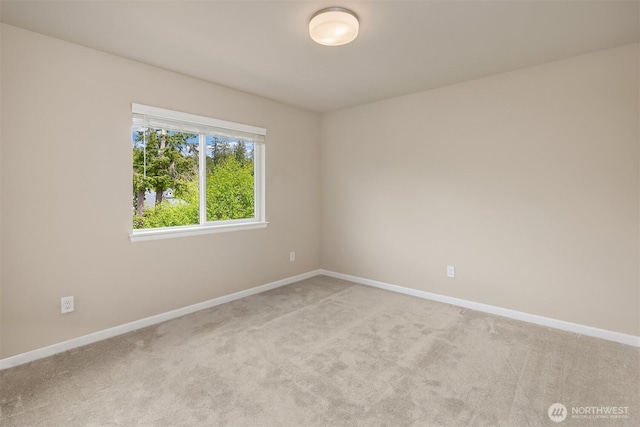 empty room featuring baseboards and light carpet