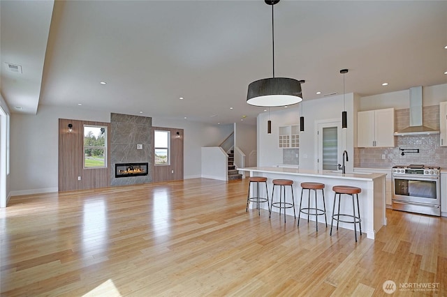 1458 Larkspur Ln, Camano Island, WA 98282 - kitchen with stainless steel gas stove, wall chimney range hood, light wood-style floors, light countertops, and recessed lighting