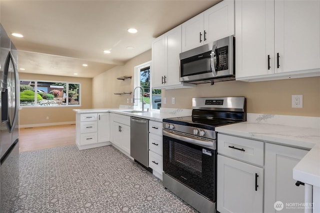 kitchen featuring stainless steel appliances, white cabinets, a sink, a peninsula, and recessed lighting
