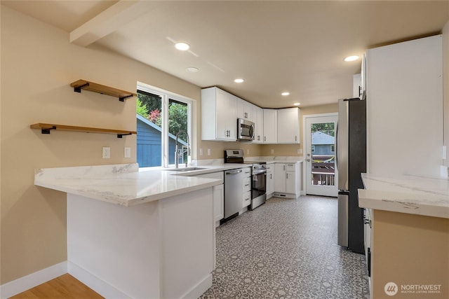 kitchen with appliances with stainless steel finishes, a sink, a peninsula, healthy amount of natural light, and recessed lighting