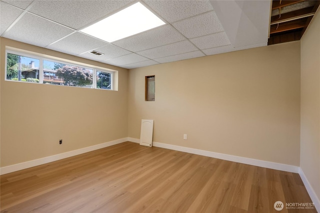 spare room with light wood-style floors, a paneled ceiling, and baseboards
