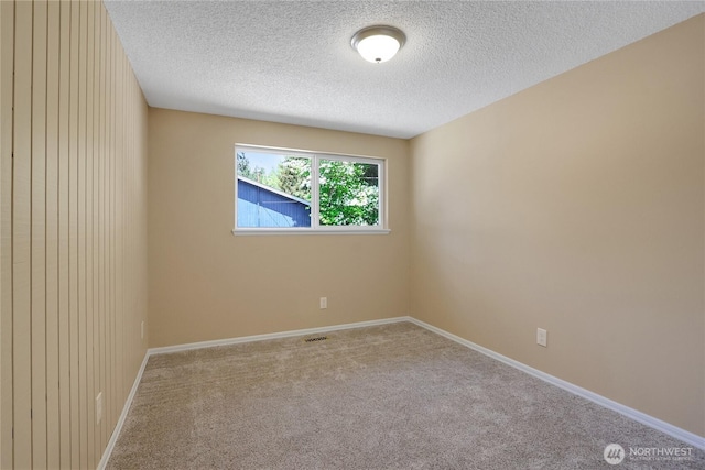 spare room with a textured ceiling, carpet floors, and baseboards