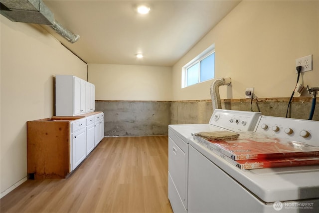 washroom with washing machine and dryer, light wood-type flooring, and cabinet space