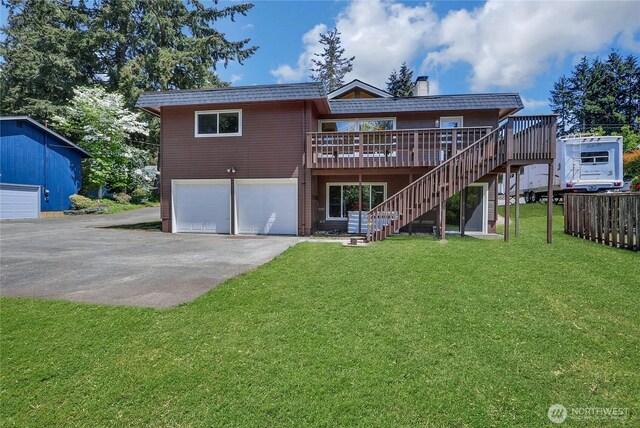 rear view of house with asphalt driveway, stairway, an attached garage, a wooden deck, and a chimney