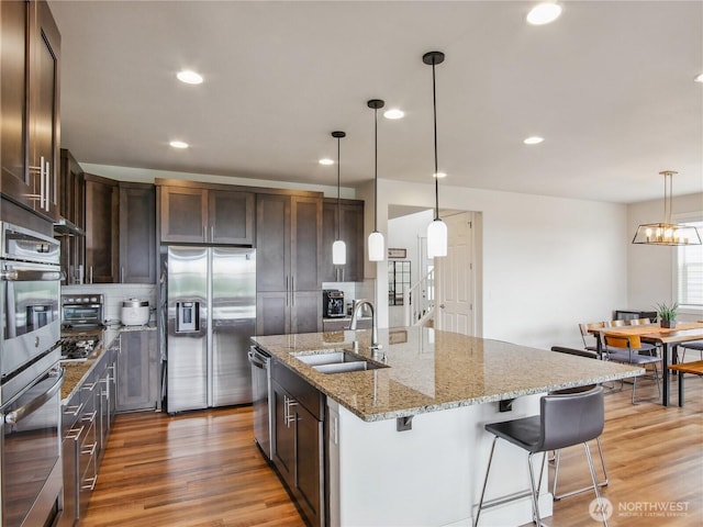 2668 83rd Avenue Ct E, Edgewood, WA 98371 - kitchen with stainless steel appliances, a sink, dark brown cabinets, light wood-type flooring, and recessed lighting