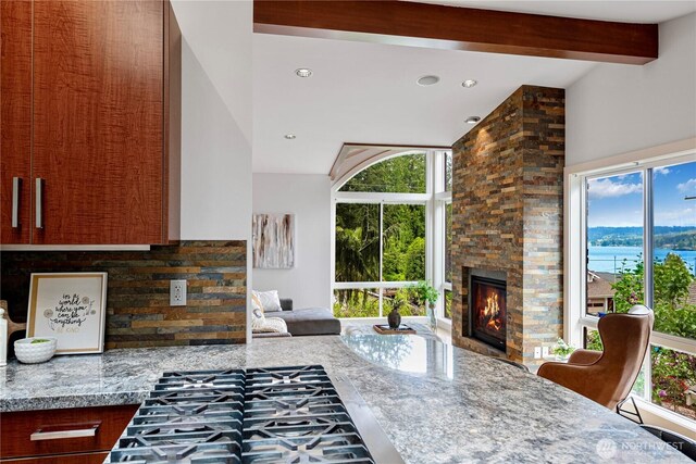 16915 SE 39th St, Bellevue, WA 98008 - living room featuring a stone fireplace, plenty of natural light, a water view, recessed lighting, and beamed ceiling