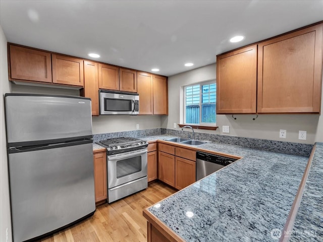 kitchen with appliances with stainless steel finishes, a sink, light wood-style floors, recessed lighting, and tile counters