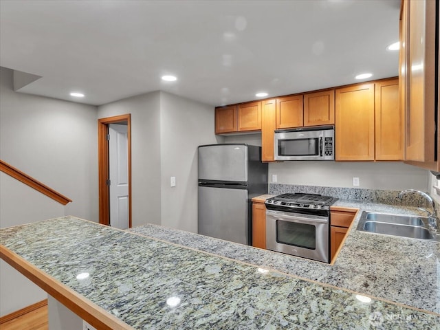 kitchen with appliances with stainless steel finishes, a sink, a peninsula, and recessed lighting